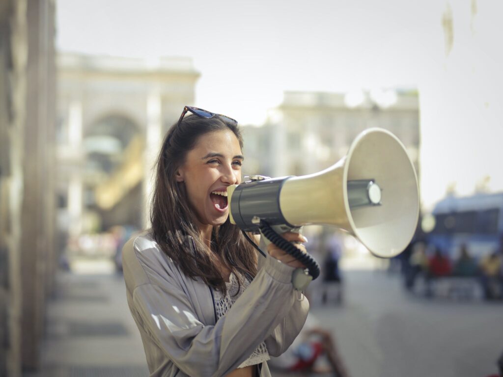 Cheerful young woman using a megaphone